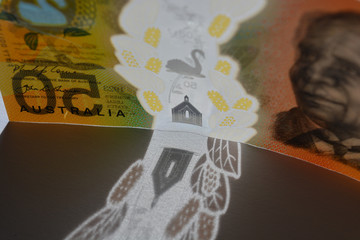 Australian fifty dollar note, standing on edge, backlit,  creating a shadow of the clear plastic security strip