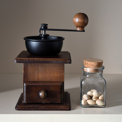 Obraz na płótnie Canvas An old hand mill and a small glass jar with pistachios.