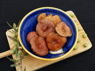 Mushrooms inside a blue ceramic bowl on a wooden table with a black background.