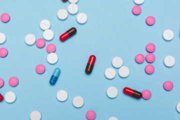 Pills / Pharmacy theme / Multicolored pills and capsules on the blue surface. Flat lay