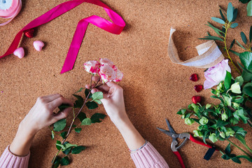 master florist prepares top-level content for the event using flowers and craft packaging in different colors, top view of layout on the table, top level event