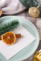 Festive Christmas and New Year details table setting with dry orange and cinnamon on a gray textile. Dining place decorated