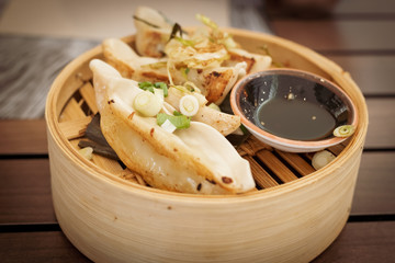 Thai food. mixed chicken, shrimp and vegetable gyozas in a Thai steamer with soy sauce in a black bowl