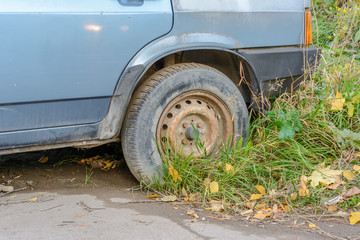 Damaged tire. The wheel of car tire leak. Flat tire waiting for repair. Abandoned car in the...