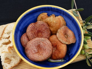Mushrooms inside a blue ceramic bowl on a wooden table with a black background.