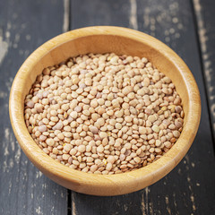 Bowl with green lentils on a white wooden background.