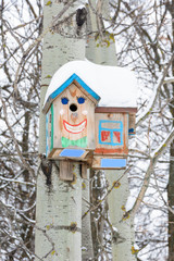 Smiley birdhouses. Birdhouse in the form of a funny face on the tree. Handmade wooden nesting box covered in snow. Winter landscape with trees covered of the snow and copy space.