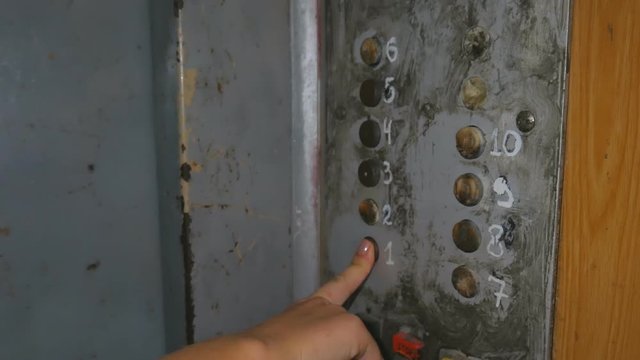 Woman at night Presses a old Button of Lift to go Up. Old metal elevator. The finger presses the button with the arrow pointed up.