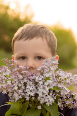 portrait of a boy with lilac. bouquet of purple lilac in children's hands. hands holding a purple lilac flowers bouquet in meadow.
