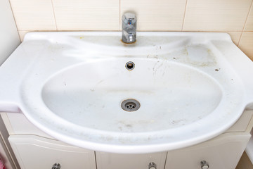 Old dirty washbasin with rust stains, limescale and soap stains in the bathroom with a faucet, water tap