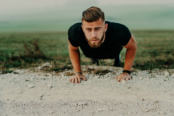 Fit man doing push ups exercise at outdoor gym. Core body workout athlete planking or doing pushup on grass.