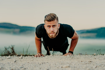 Fit man doing push ups exercise at outdoor gym. Core body workout athlete planking or doing pushup on grass.