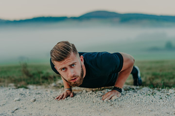 Fit man doing push ups exercise at outdoor gym. Core body workout athlete planking or doing pushup on grass.