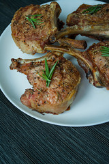 Grilled steaks from pork ribs with spices and herbs. Side view. Dark wooden background.
