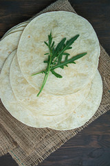 Flat cakes for tacos or burritos. Pita bread for making tacos. Dark wooden background.