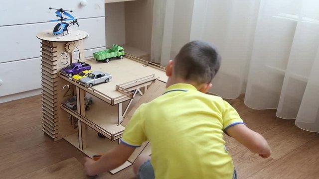 Preschool boy playing in the children's room with cars on the wooden Parking lot