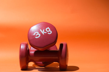 two 3 kg weights on orange background
