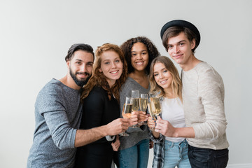 Young cheerful friendly men and women toasting with flutes of champagne