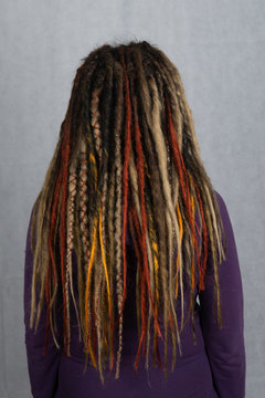 Woman with long dreadlocks shot from behind. Rear view of hairstyle dreadlocks. dreadlocks on the head of a young girl. Girl with the African pigtails.