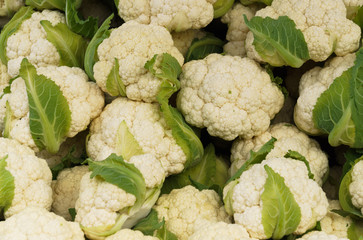 White cauliflower with green leaves in a crate on the market.