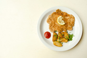 Fried potato with chicken chop and drop of tomato sauce. Roasted potato wedges. Garnish with meat. Tasty lunch dish close up