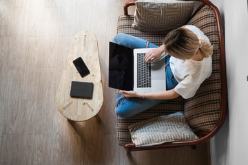 Woman with a laptop sitting on a sofa. Study and work online, freelance. Self employed woman, girl...