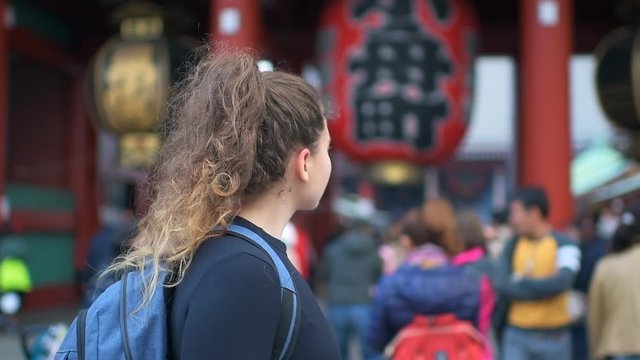 Tokyo, Japan - March 30, 2018: Asakusa area with young caucasian girl woman by Sensoji temple shrine gate entrance with red architecture panning up in slow motion