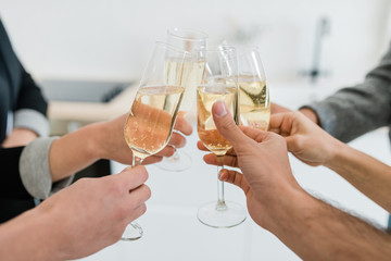 Hands of friends holding flutes of sparkling of champagne and clinking with them