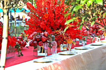 Autumn harvest decorated table in red color. Decoration with red apples and pomegranate. Stylish interior design.
