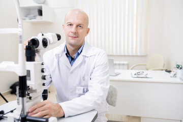 Naklejka na ściany i meble Successful professional optometrist working with new eyesight check-up equipment