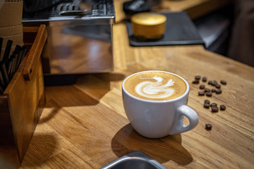 Abstract pattern on cappuccino or latte cup on wooden table in a vintage cafe with coffee beans at the backgroung