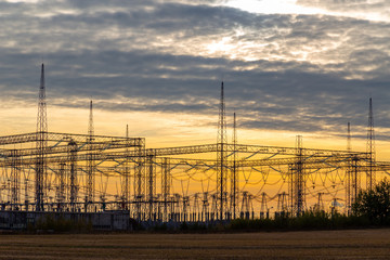 Electrical sub station against sunset sky with clouds. Electericity generation and polution.