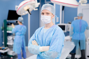 Young successful male surgeon or intern in protective mask and uniform