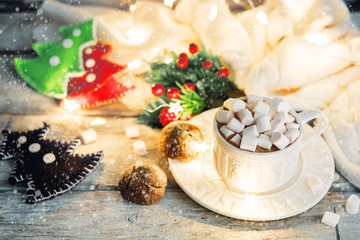 Fototapeta na wymiar Christmas holidays wood background with Cup of Cocoa with marshmallow, luminous garland and cookie