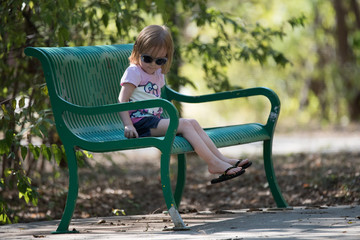 Little girl on park bench with sunglasses