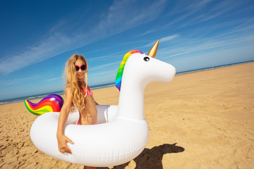 Girl with inflatable toy unicorn on sea beach © Sergey Novikov