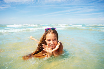 Fototapeta na wymiar Cute girl play in waves holding palms near face