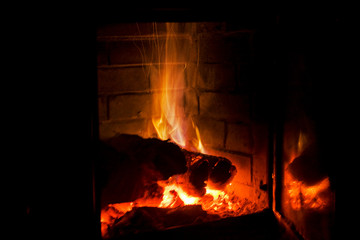 fire burns with wood in a fireplace with blue gas on a black background, holiday of lights, christmas, horizontal