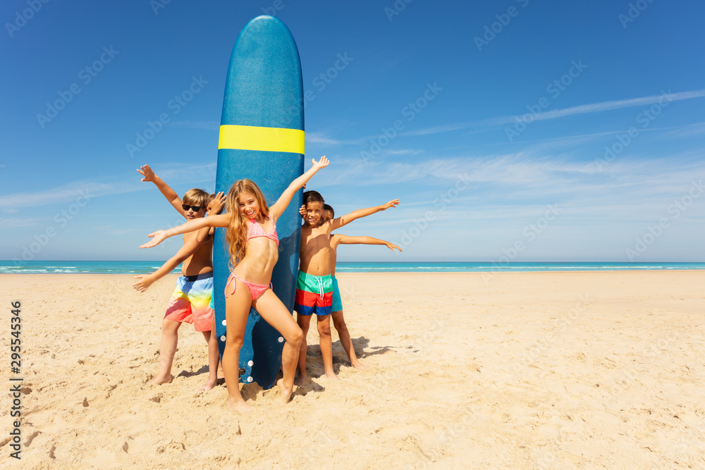 Wall mural Group of kids stand waving hands near surfboard