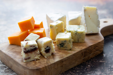 Various different types of cheese slices, cheese mix on wooden cutting board. Wine snack. Camembert, parmesan, brie cheese.