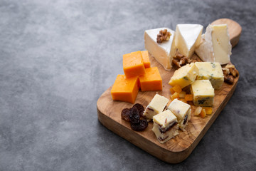 Various different types of cheese slices, cheese mix on wooden cutting board. Copy space. Camembert, parmesan, brie cheese.