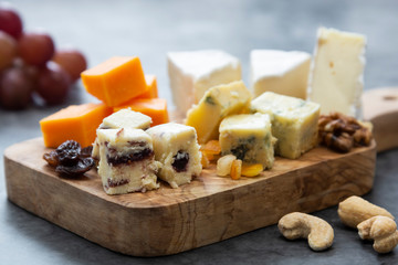 Various different types of cheese slices, cheese mix on wooden cutting board. Wine snack. Camembert, parmesan, brie cheese.