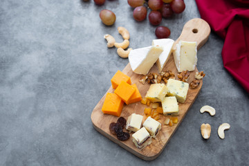 Various different types of cheese slices, cheese mix on wooden cutting board. Copy space. Camembert, parmesan, brie cheese.