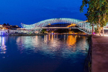 Fototapeta na wymiar TBILISI, GEORGIA - JULY 15, 2017: Evening view of the Peace Bridge in Tbilisi, Georgia
