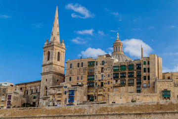 Fototapeta na wymiar Tower of St Paul's Pro-Cathedral and the cupola of the Basilica of Our Lady of Mount Carmel in Valletta, Malta