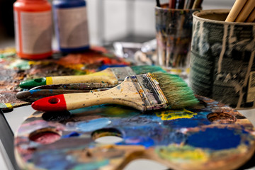 Group of paintbrushes and palettes on background of gouache jars