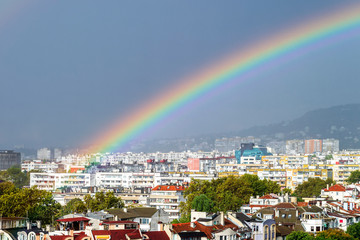Close-up of gorgeous rainbow over residential area of the city. Scenic summer cityscape with a rainbow.