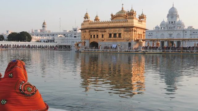 180p slow motion clip of golden temple reflections in amritsar, india, with sikh woman in the foreground