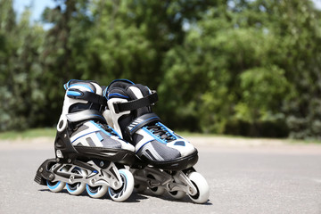 Fototapeta na wymiar Modern inline roller skates in city park on sunny day