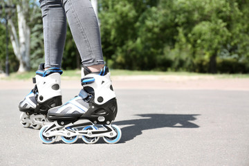 Woman with modern inline roller skates in city park, closeup